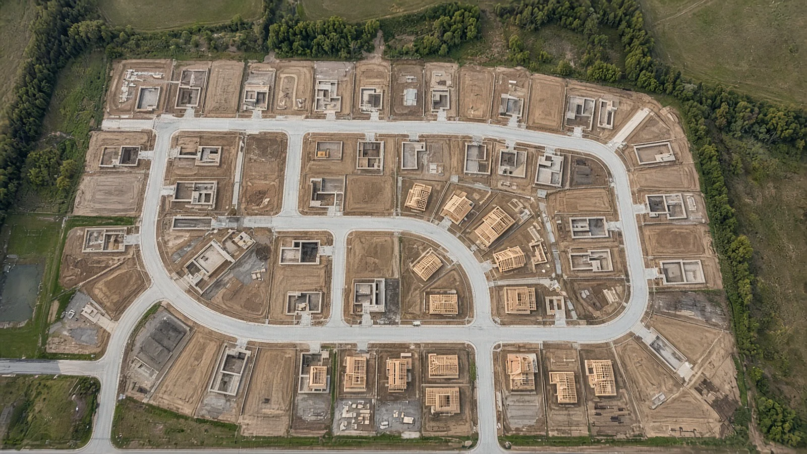 Top-down aerial view of a new residential subdivision with graded lots, fresh streets and framed homes